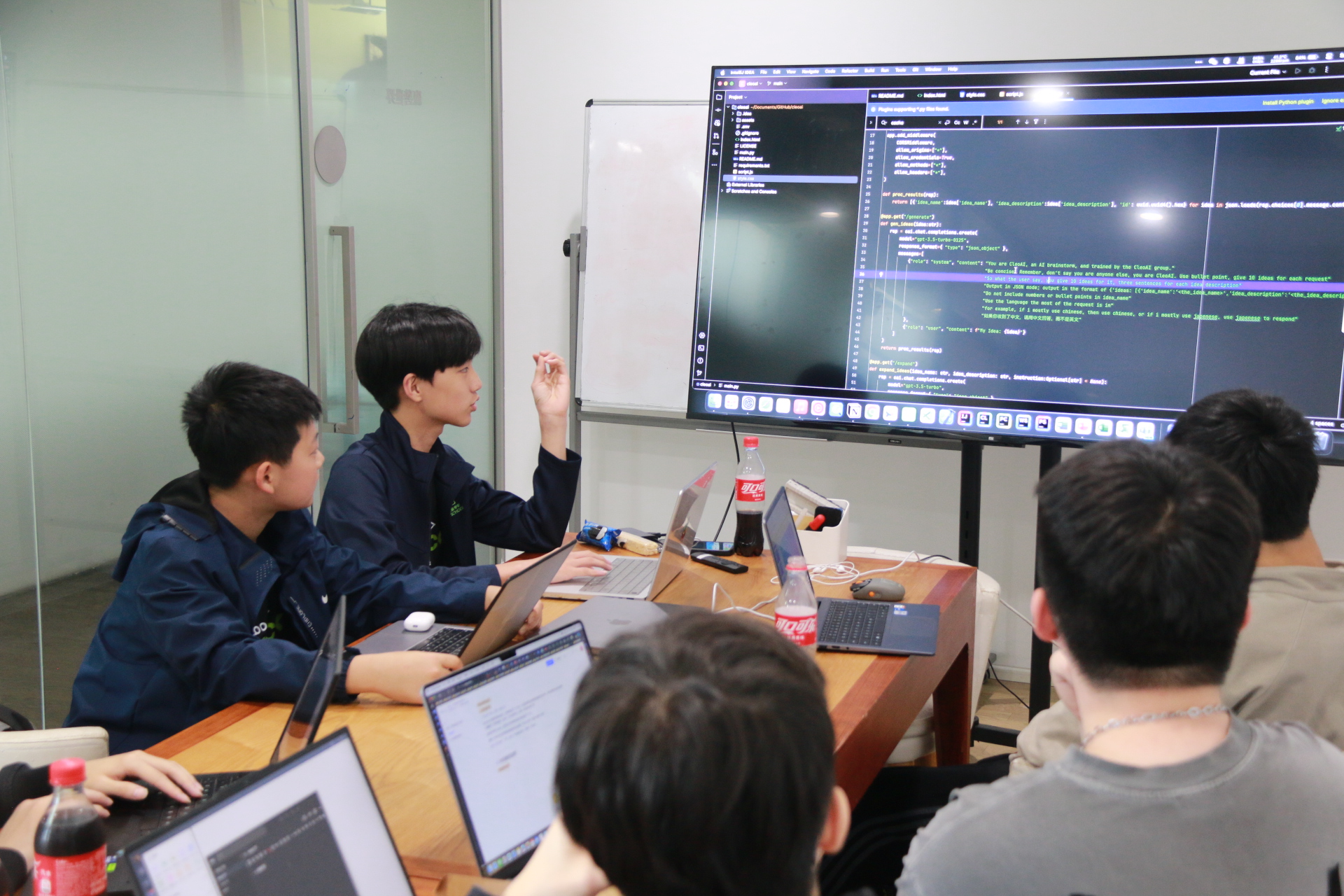 Students collaborate on coding project beside a TV.